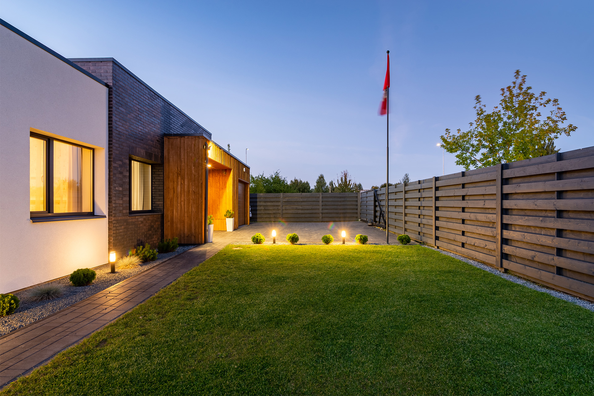 Zaun und Gartentor aus Holz vor einem modernen Einfamilienhaus